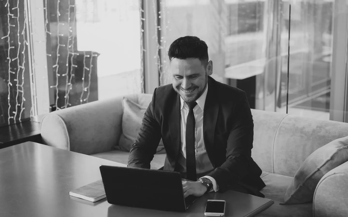 A man in a suit working at a laptop in a modern office, in black and white